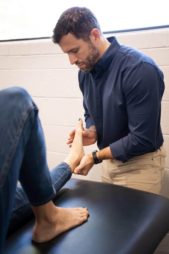 physical therapist in Tucson examining a patient’s foot for heel pain to differentiate plantar fasciitis from flexor digitorum brevis injury