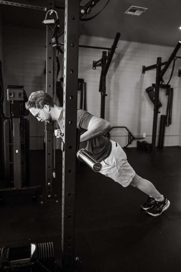 Black and white photo of Kenny Sewall performing an elevated push-up at a gym station in Smith Performance Center, showcasing strength and form.